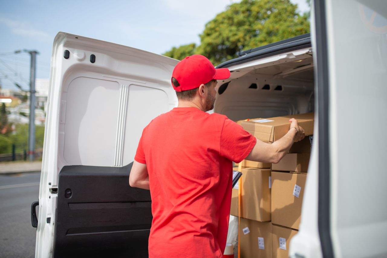 services-04 Courier carrying packages into a van for delivery, wearing a red uniform.